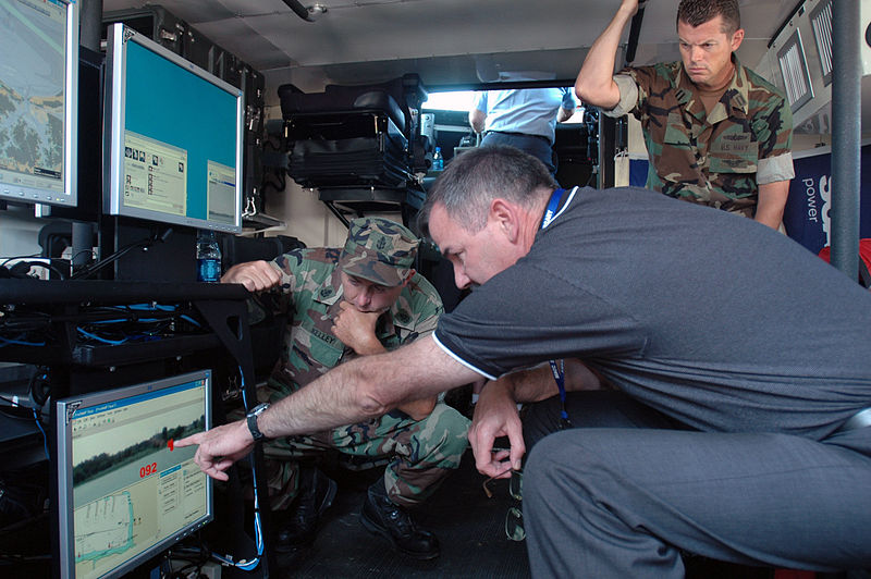US Navy 070606-N-2456S-225 Jerry Fitzmorris, Raytheon Program Manager shows computer systems to Senior Chief Electronics Technician Scott Kelley, and Lt. William Swinford, during the Multi-Agency Craft Conference (MACC) June 6